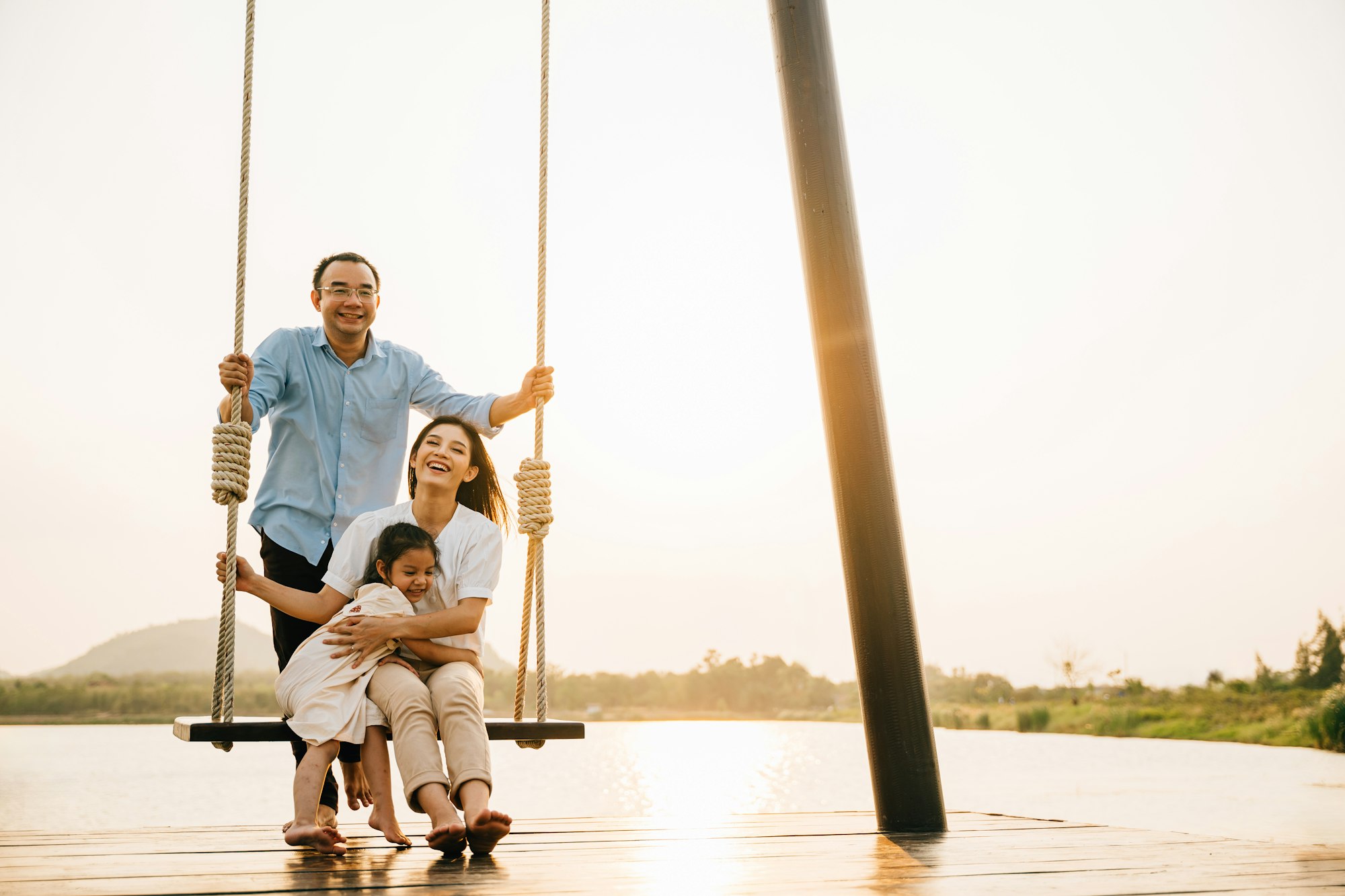 Asian family swinging on a swing in a serene nature setting