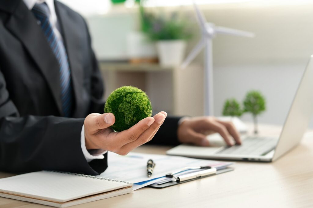 Businessman holds a green ball globe. ESG concept. Environmental, social and governance
